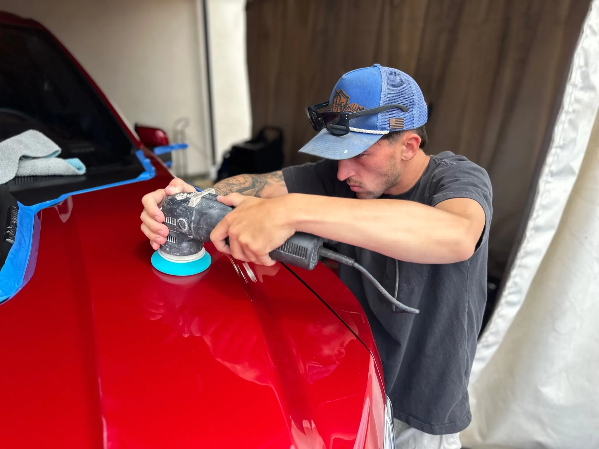 Max Spain machine-polishing the hood of a red car